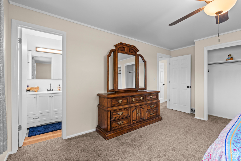 Bedroom featuring carpet floors, ensuite bathroom, crown molding, baseboards, and a closet