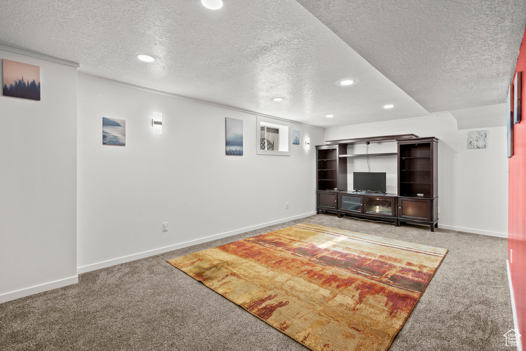 Unfurnished living room featuring a textured ceiling, carpet flooring, recessed lighting, and baseboards