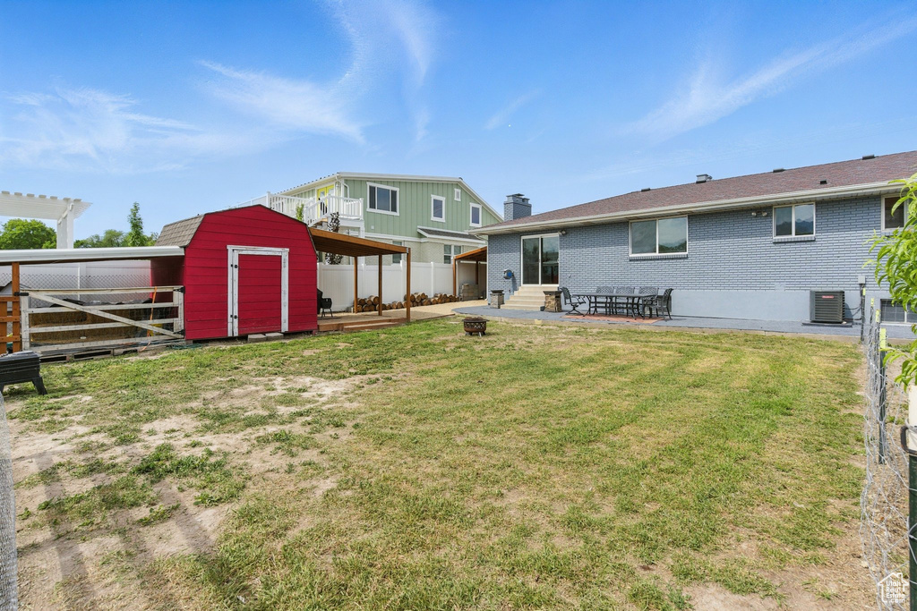 Back of house featuring brick siding, a chimney, a patio area, and central air condition unit