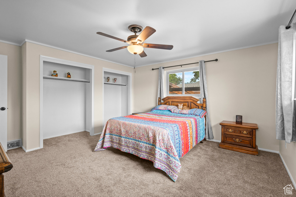 Carpeted bedroom featuring ceiling fan, crown molding, and baseboards