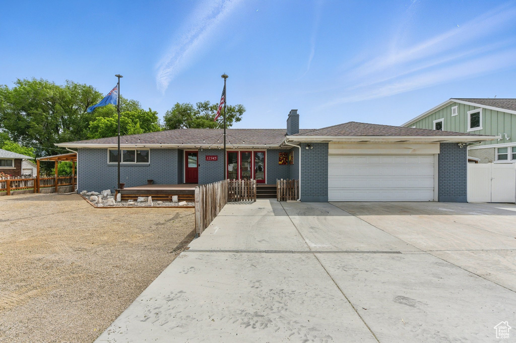 Single story home featuring an attached garage, a chimney, concrete driveway, and brick siding