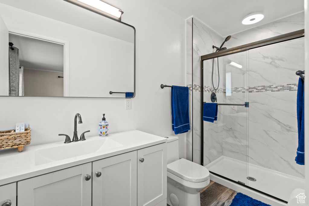 Full bath with a marble finish shower, vanity, toilet, and wood finished floors