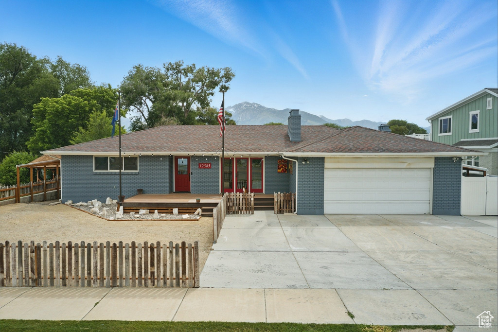 Single story home with an attached garage, a chimney, brick siding, and driveway
