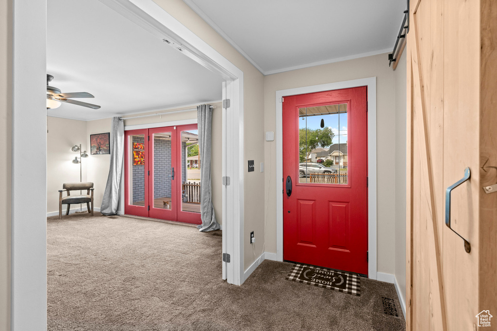 Foyer entrance featuring carpet flooring, healthy amount of natural light, baseboards, and crown molding
