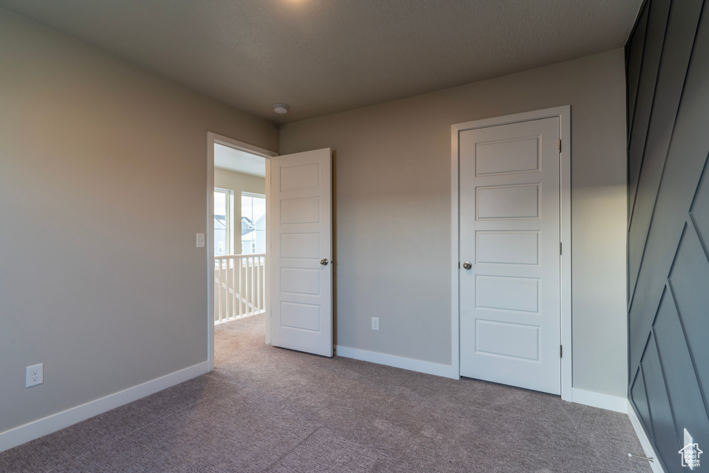 Unfurnished bedroom with carpet flooring and baseboards