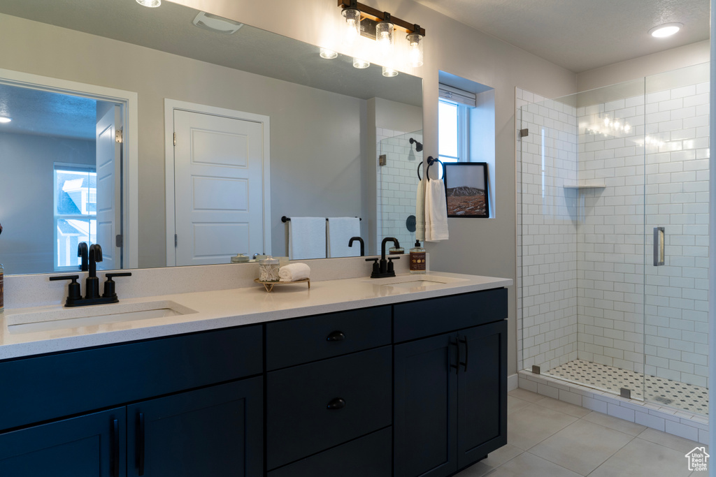 Full bath with a stall shower, double vanity, and tile patterned floors