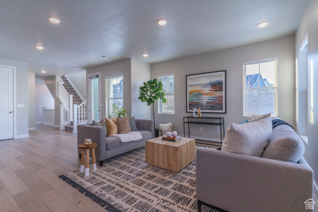Living area with stairway, light wood-style floors, recessed lighting, baseboards, and healthy amount of natural light