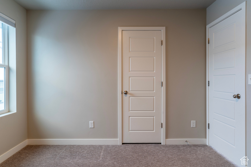 Unfurnished bedroom with carpet flooring and baseboards