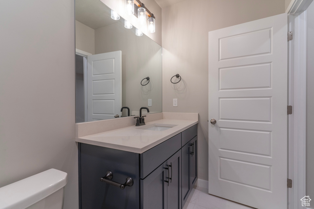 Half bathroom featuring vanity, toilet, baseboards, and tile patterned floors