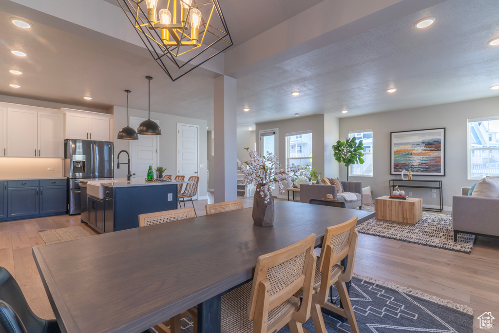 Dining room with healthy amount of natural light, light wood finished floors, recessed lighting, and a chandelier
