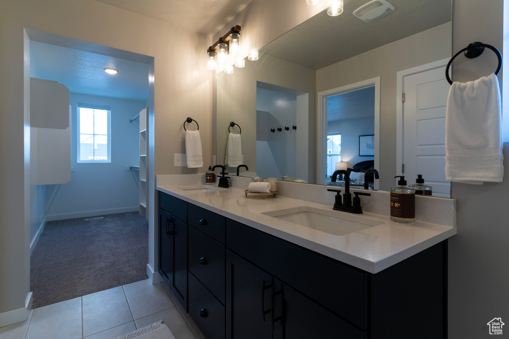 Bathroom with double vanity, baseboards, tile patterned flooring, and a shower