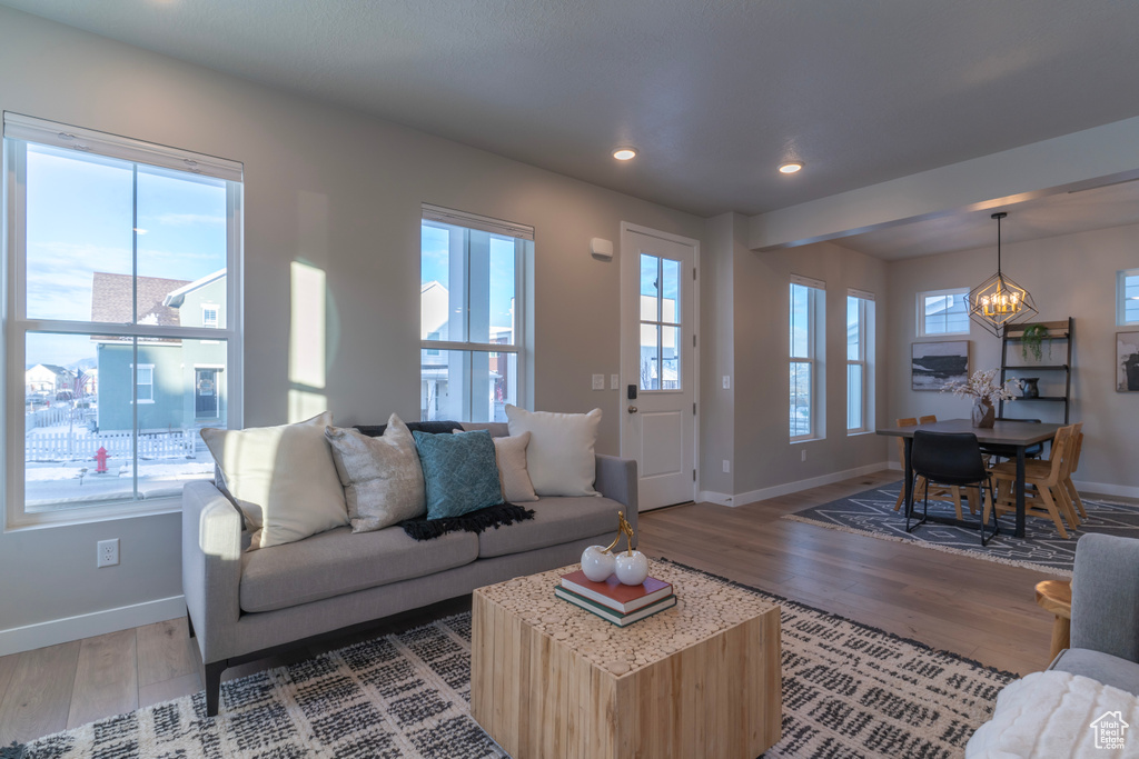 Living area with baseboards, light wood finished floors, a chandelier, and recessed lighting