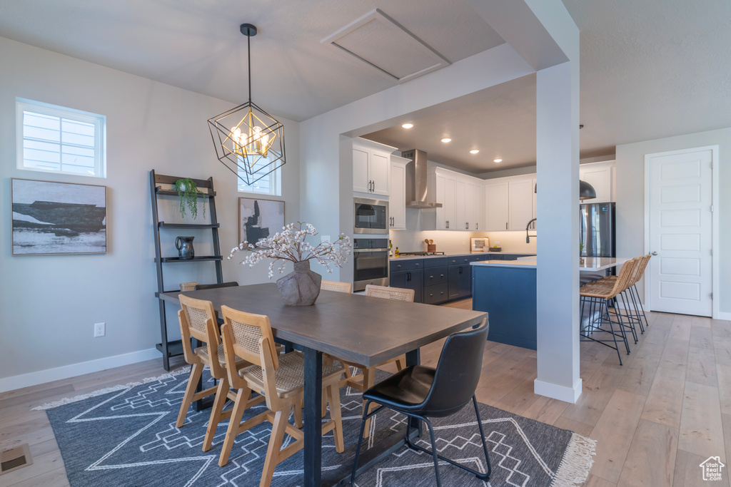 Dining room featuring light wood-type flooring, baseboards, a chandelier, and recessed lighting