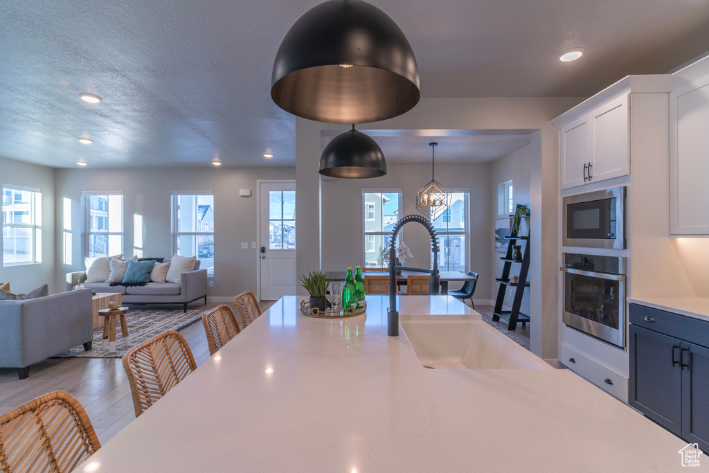 Kitchen with appliances with stainless steel finishes, a sink, light countertops, recessed lighting, and white cabinets