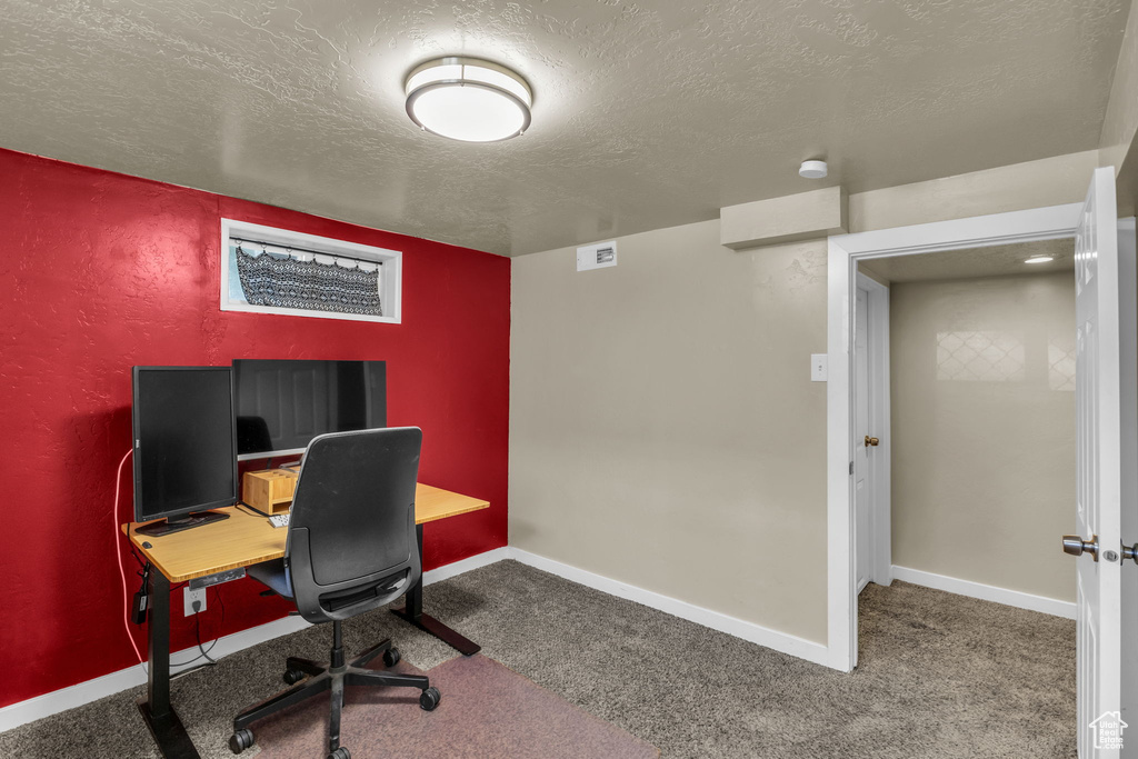 Carpeted office space featuring a textured ceiling and baseboards