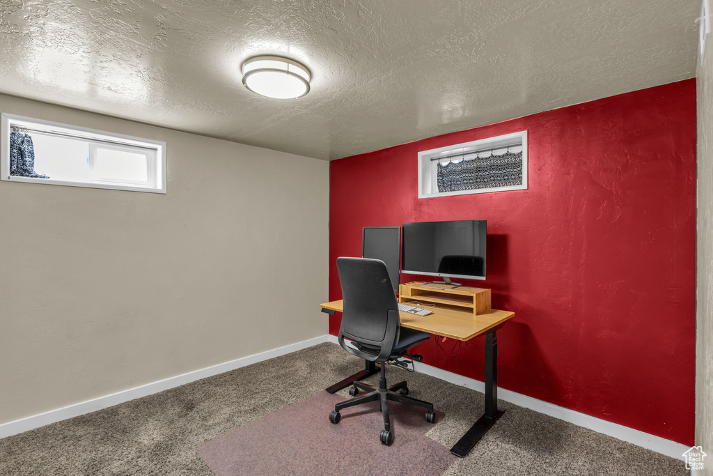 Carpeted office featuring a textured ceiling and baseboards