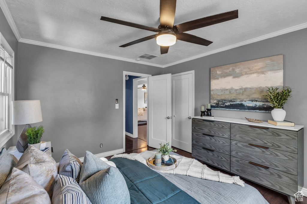 Bedroom with wood finished floors, baseboards, ceiling fan, ornamental molding, and a textured ceiling