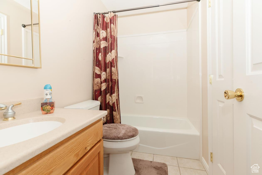 Full bath with toilet, tile patterned flooring, vanity, and shower / bath combo