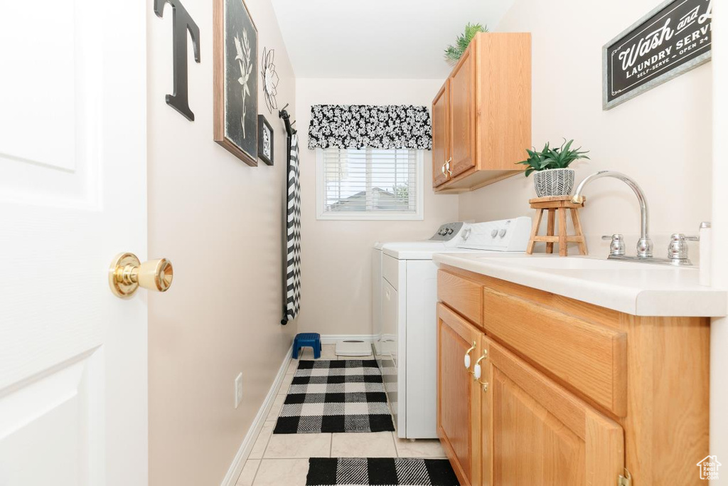 Washroom with cabinet space, washing machine and clothes dryer, light tile patterned flooring, and baseboards