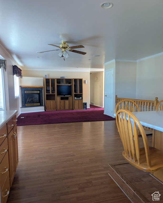 Living area with ornamental molding, ceiling fan, dark wood finished floors, a glass covered fireplace, and recessed lighting