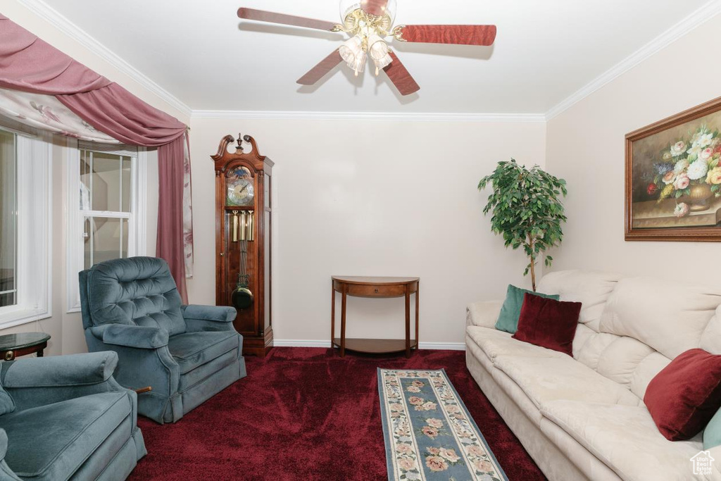 Carpeted living area featuring crown molding, a ceiling fan, and baseboards