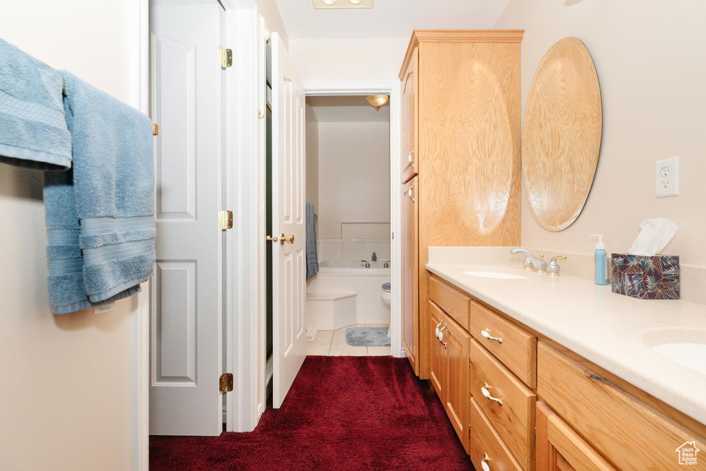 Full bath featuring double vanity, toilet, a bath, and tile patterned floors