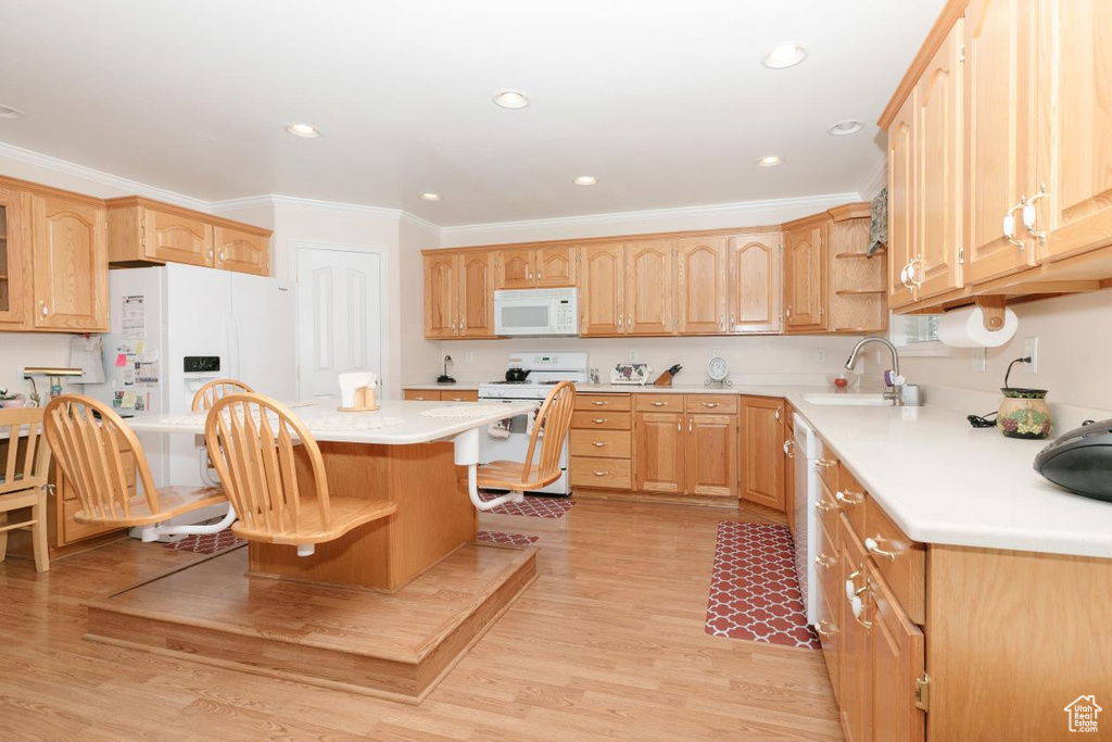 Kitchen with white appliances, a sink, ornamental molding, light countertops, and a kitchen bar