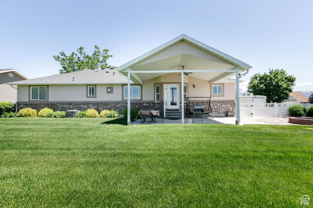 Back of property with stucco siding, a ceiling fan, a patio area, and stone siding