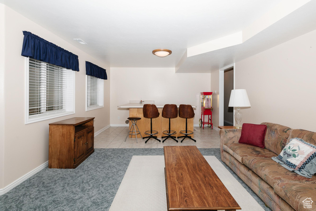 Living area featuring baseboards, bar, and light colored carpet