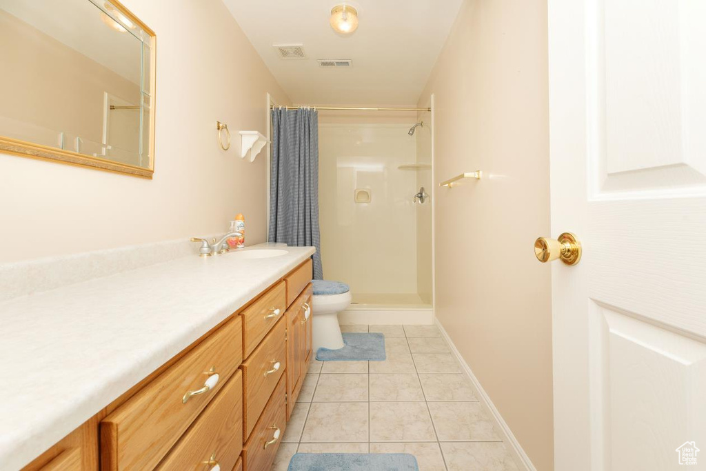Full bathroom with vanity, a shower with shower curtain, tile patterned floors, toilet, and baseboards