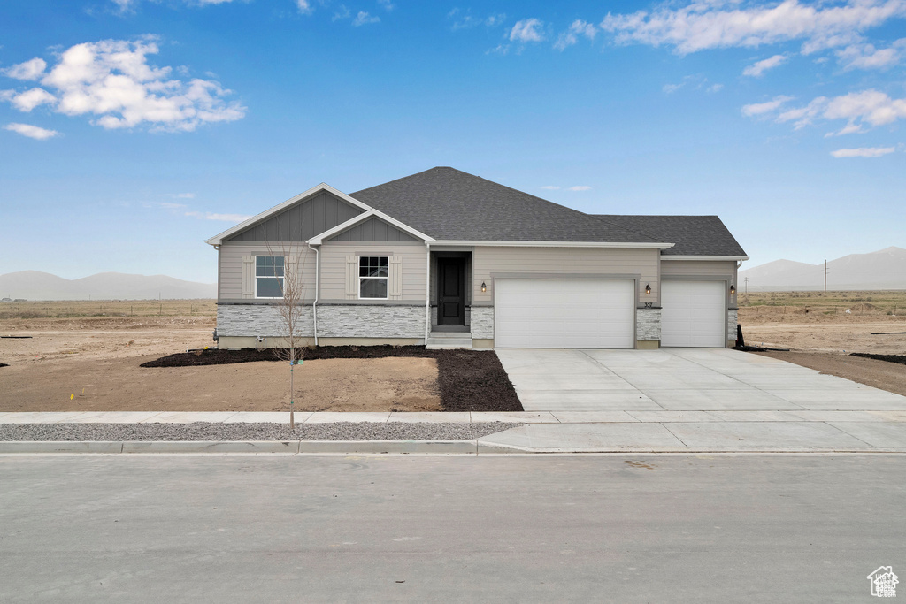 View of front of house featuring an attached garage, a mountain view, concrete driveway, and board and batten siding