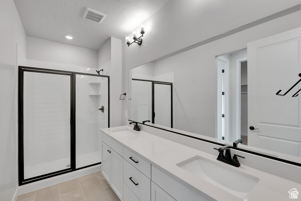 Full bath with a stall shower, double vanity, tile patterned floors, and recessed lighting