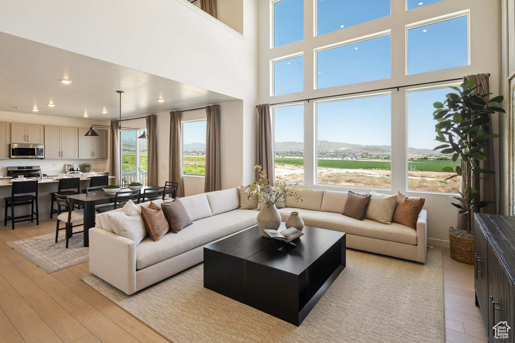 Living area featuring light wood-type flooring, recessed lighting, and a high ceiling