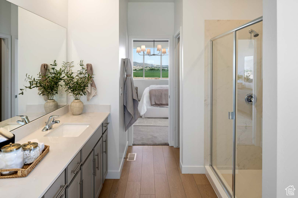 Full bathroom with ensuite bathroom, vanity, a shower stall, wood finished floors, and baseboards