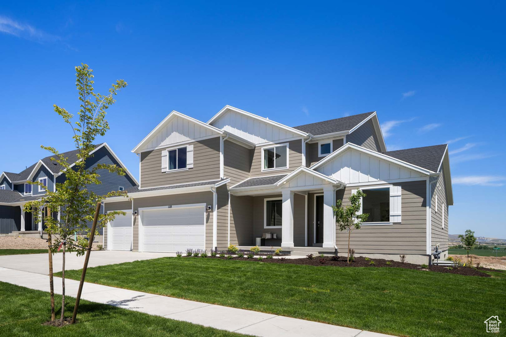 View of front of house featuring board and batten siding, a porch, an attached garage, driveway, and a front lawn