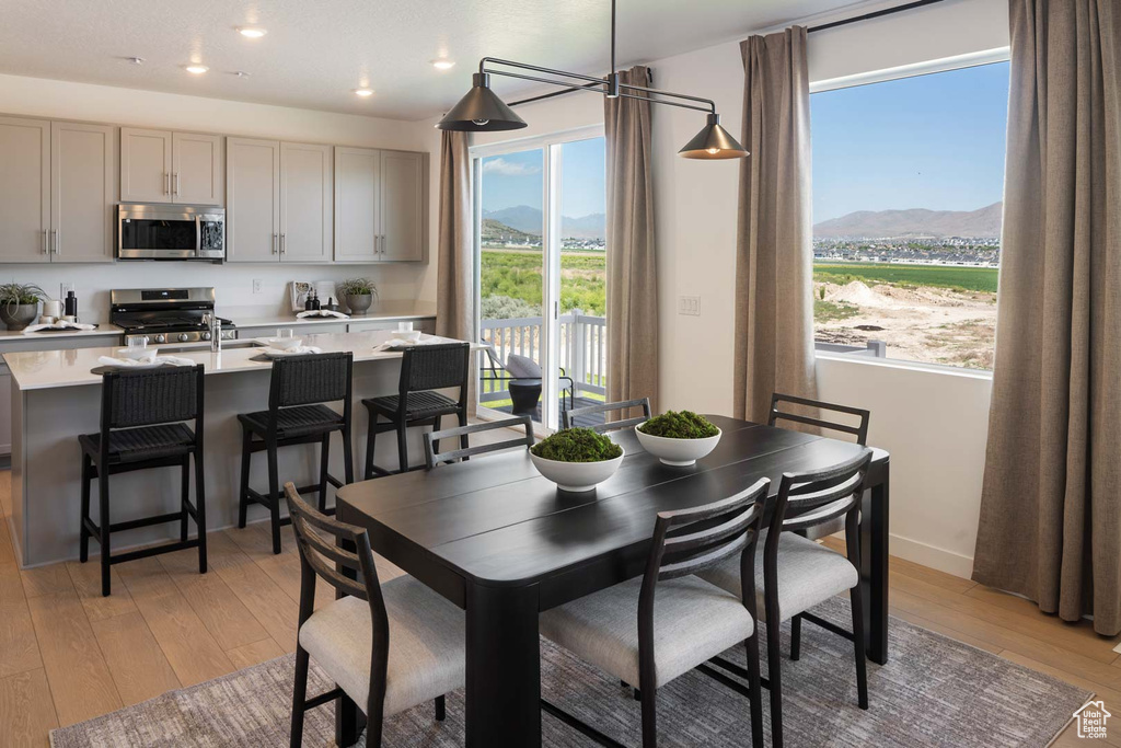 Dining space with a mountain view, healthy amount of natural light, light wood finished floors, recessed lighting, and baseboards
