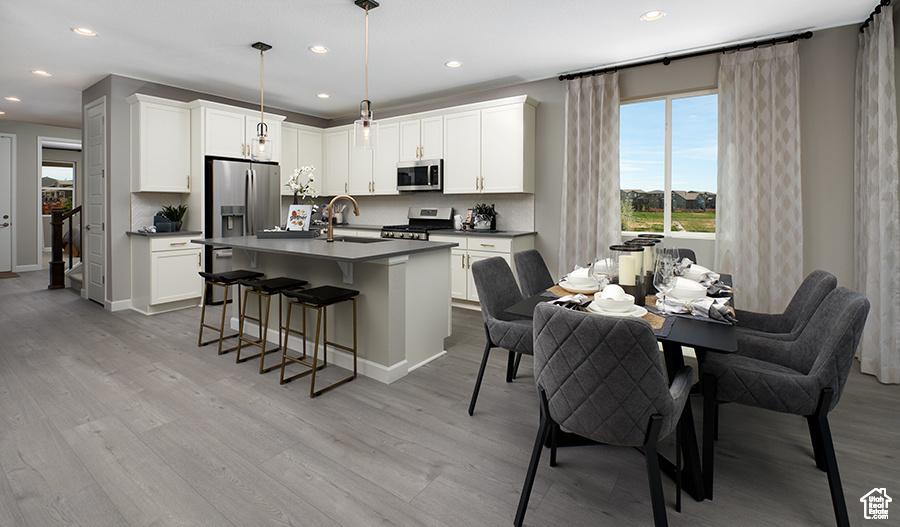 Kitchen with stainless steel appliances, a sink, tasteful backsplash, dark countertops, and light wood-style floors
