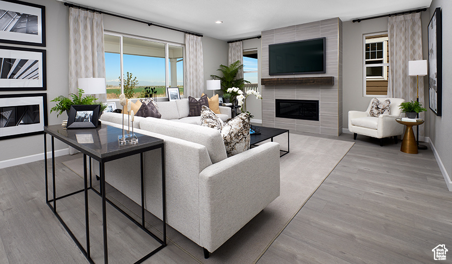 Living room featuring baseboards, wood finished floors, a tiled fireplace, and recessed lighting