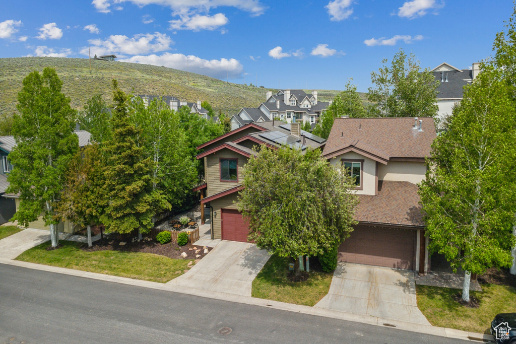View of front of house featuring driveway, an attached garage, a residential view, and stucco siding