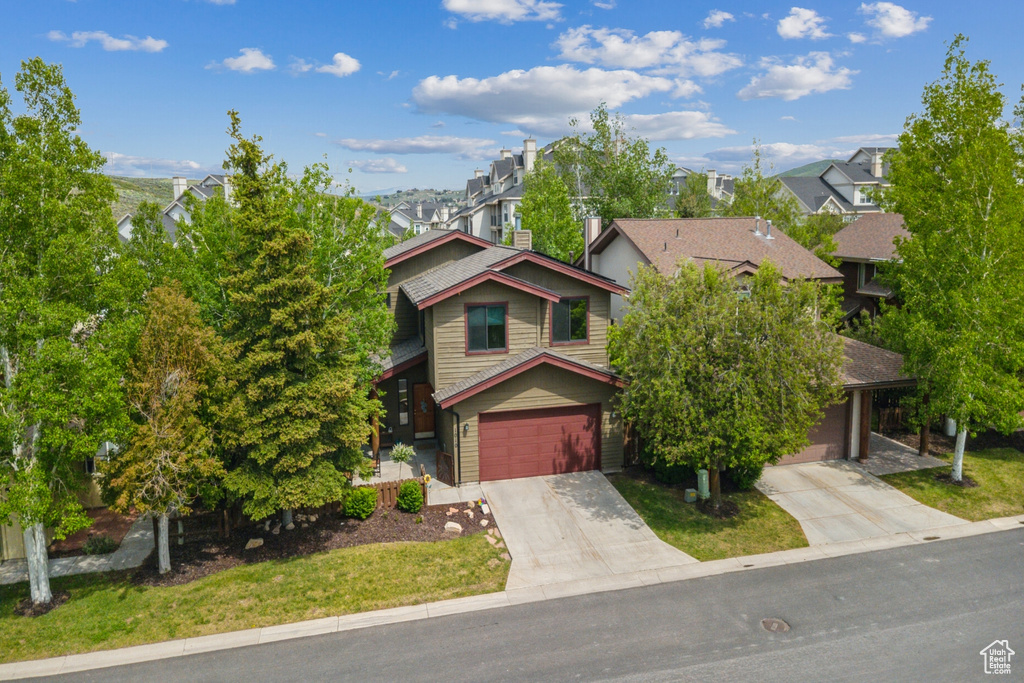 View of front of property featuring concrete driveway, a residential view, and a garage