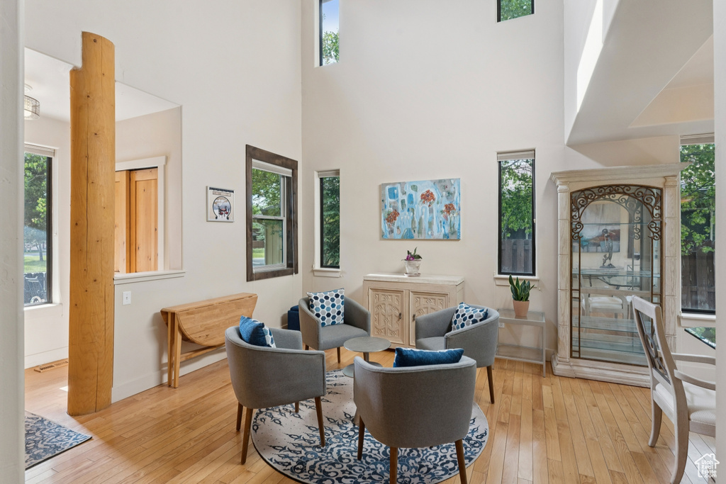 Sitting room with light wood-style floors, a towering ceiling, and baseboards
