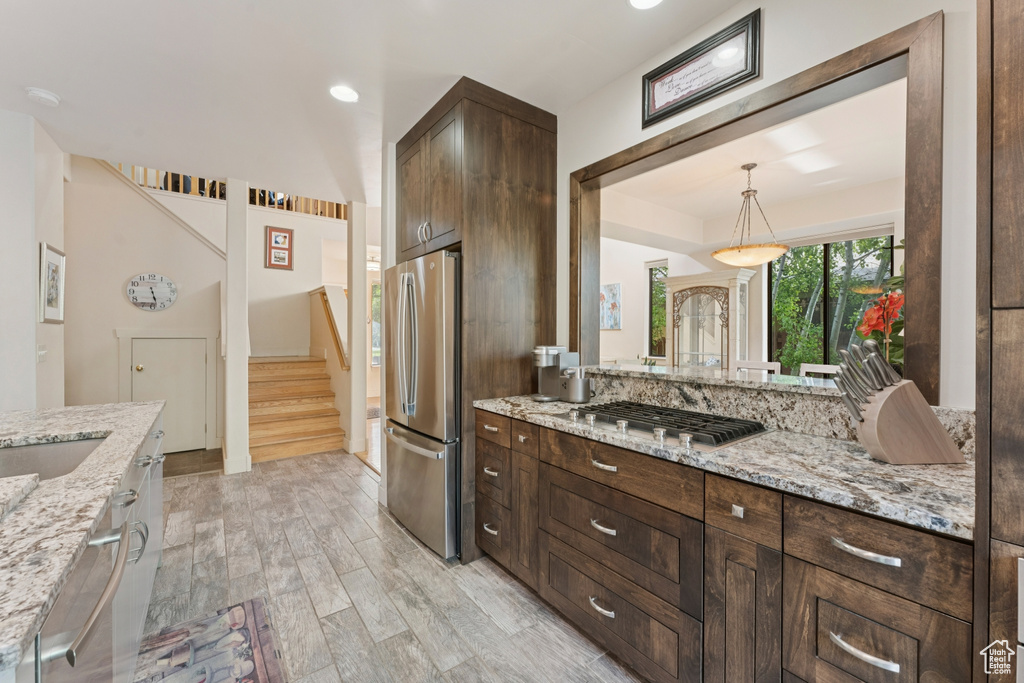 Kitchen with stainless steel appliances, dark brown cabinetry, light wood finished floors, hanging light fixtures, and recessed lighting