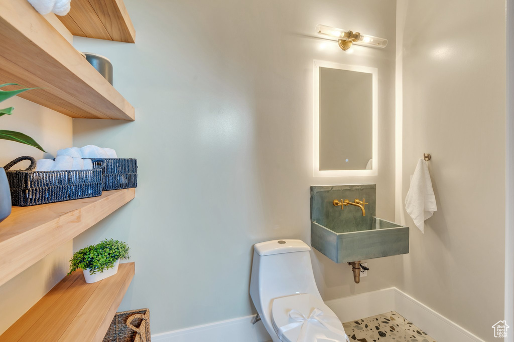 Bathroom featuring toilet, baseboards, and a sink