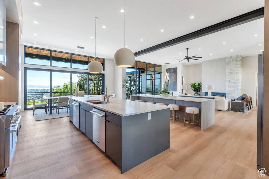 Kitchen featuring a large island, open floor plan, modern cabinets, appliances with stainless steel finishes, and light wood-style floors