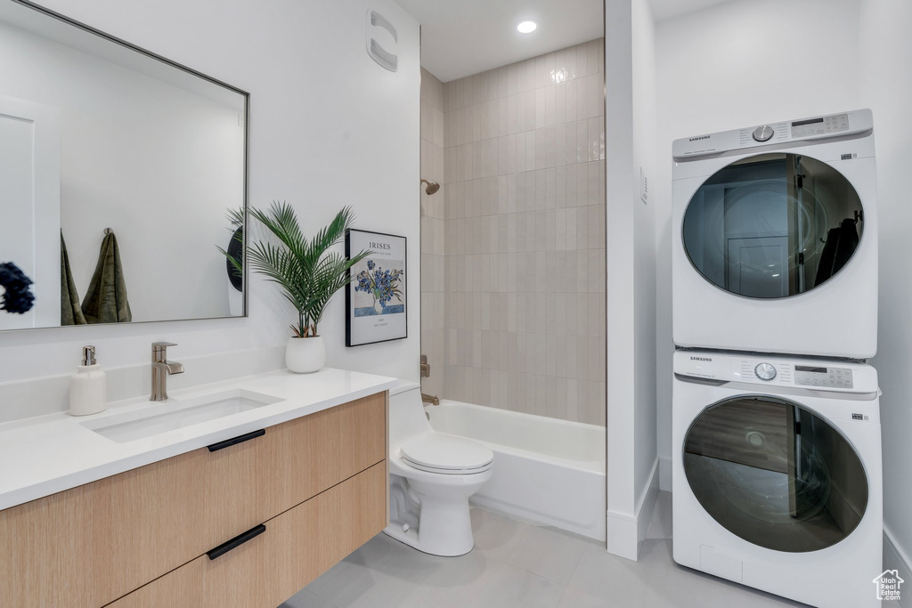 Bathroom with stacked washer and clothes dryer, vanity, toilet, bathing tub / shower combination, and recessed lighting
