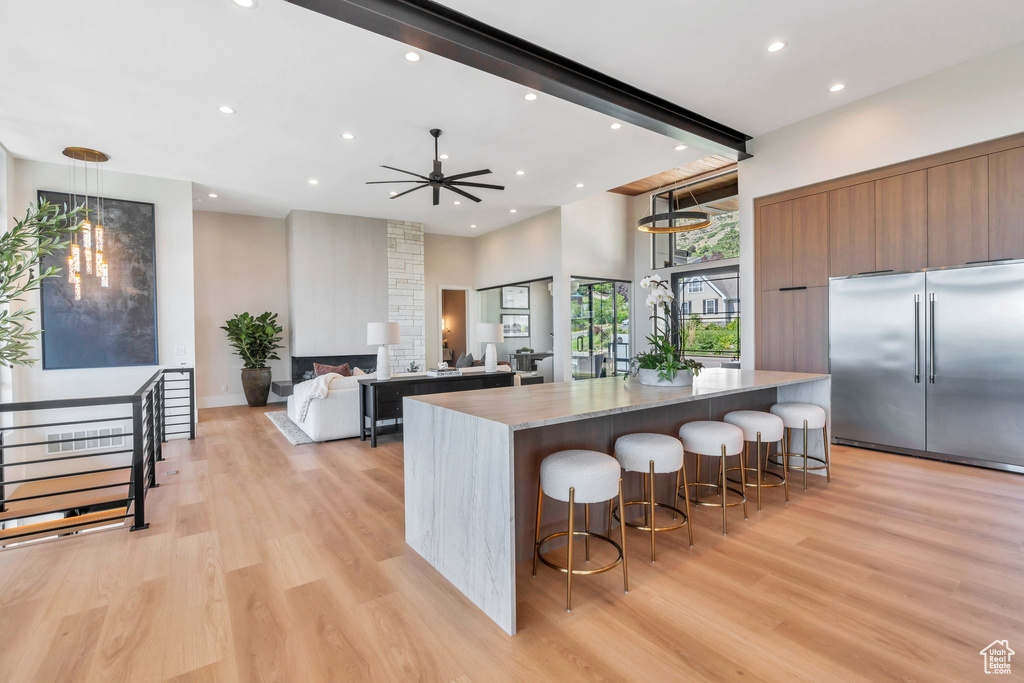 Kitchen with stainless steel built in fridge, modern cabinets, recessed lighting, light wood-type flooring, and a breakfast bar area