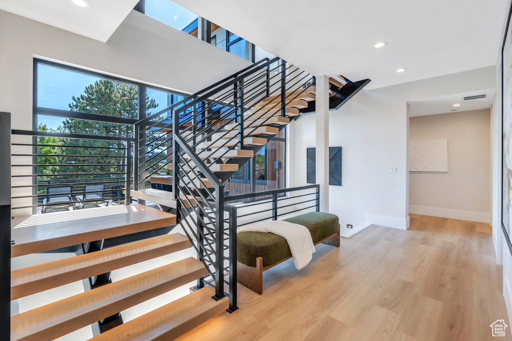 Stairway featuring baseboards, wood finished floors, and recessed lighting