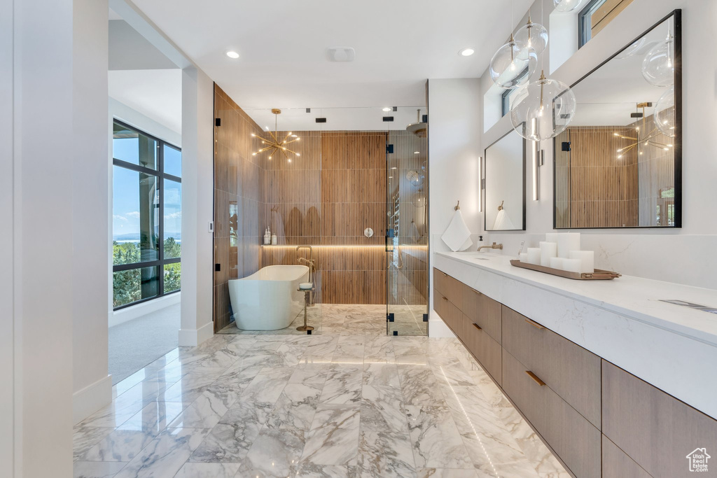 Full bath with a stall shower, a freestanding bath, vanity, recessed lighting, and marble tiled floors
