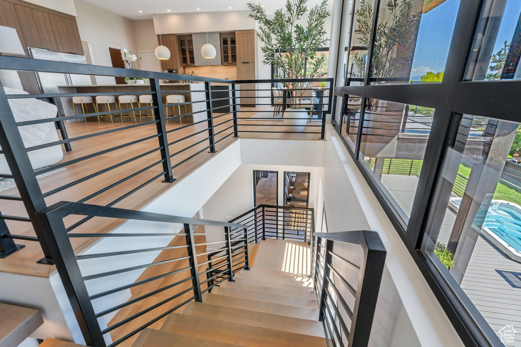 Stairs featuring plenty of natural light, wood finished floors, a high ceiling, and recessed lighting