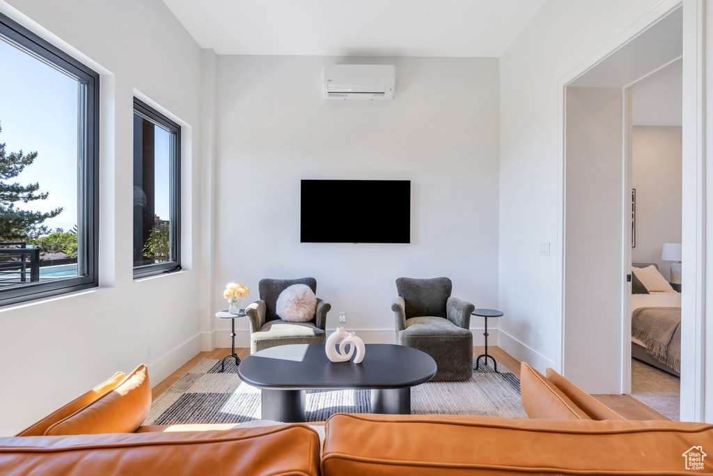 Sitting room featuring a wall mounted AC, wood finished floors, and baseboards